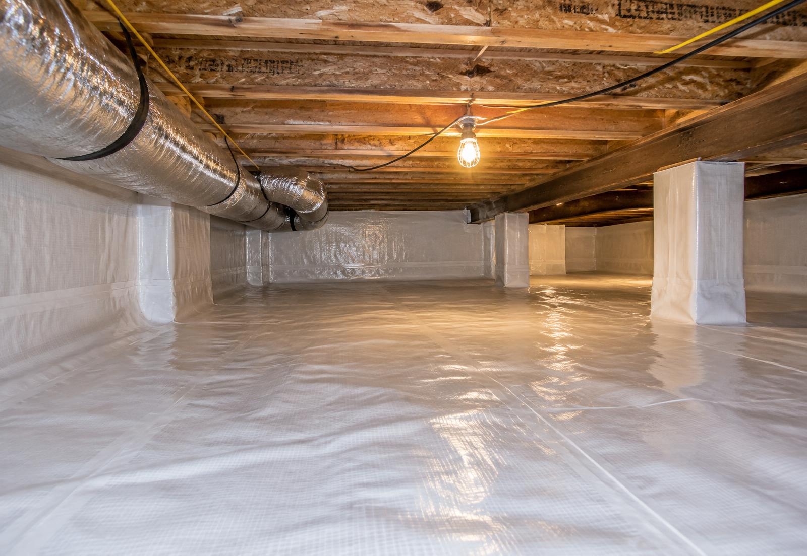 Crawl space lined with a white reinforced vapor barrier across the ground and foundation walls